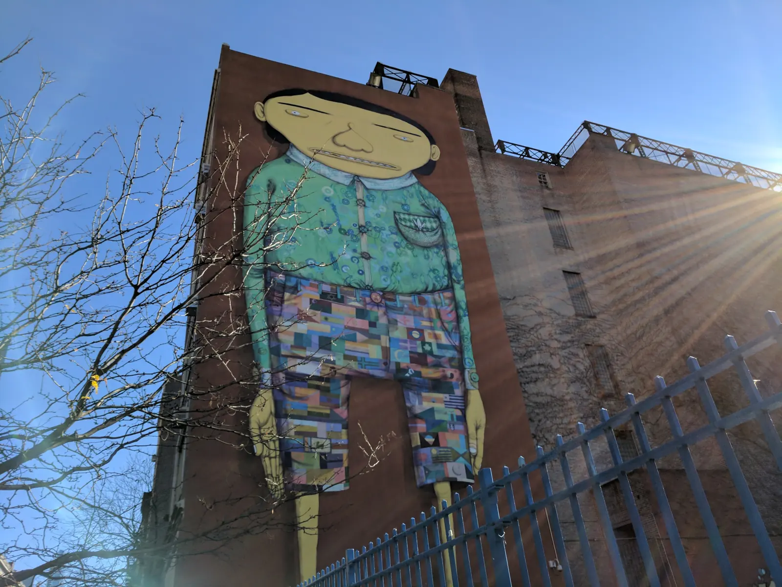 A giant painted figure in patchwork shorts on a brick building in downtown Manhattan